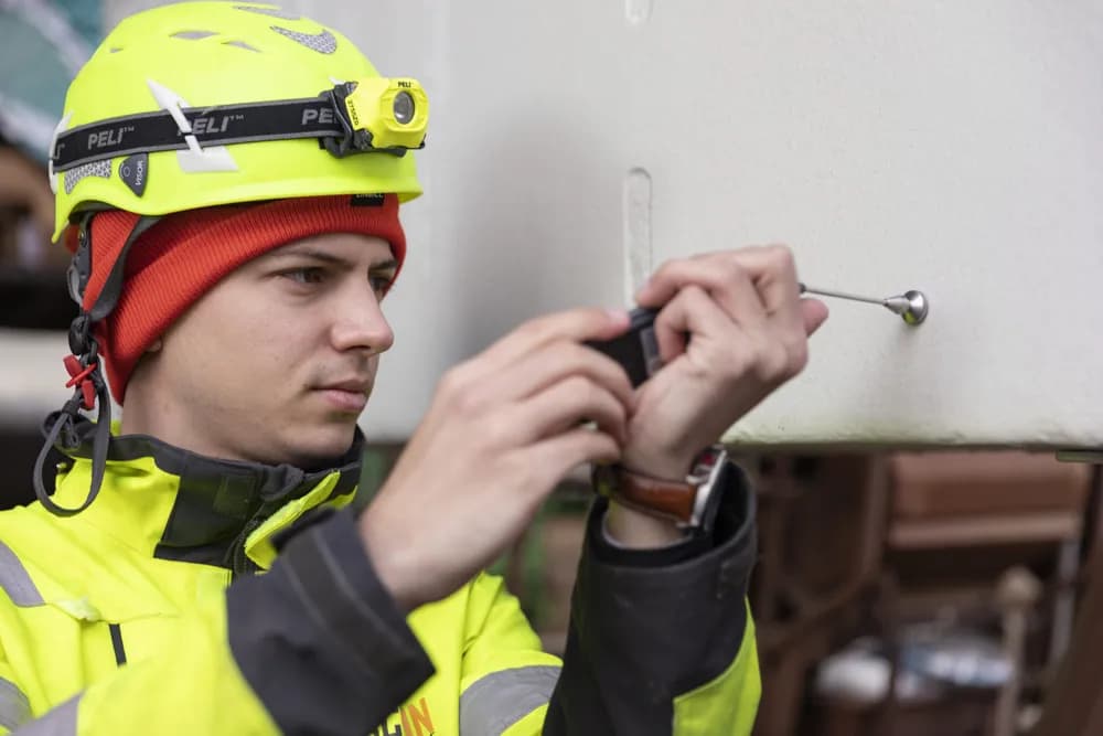 Beau Ackx in a helmet and head torch inspecting a surface